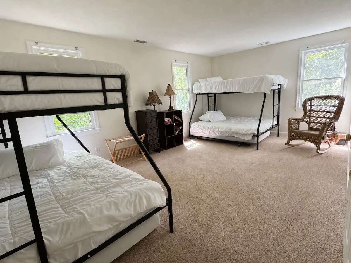 A large carpeted room with two sets of bunk beds and a rocking chair