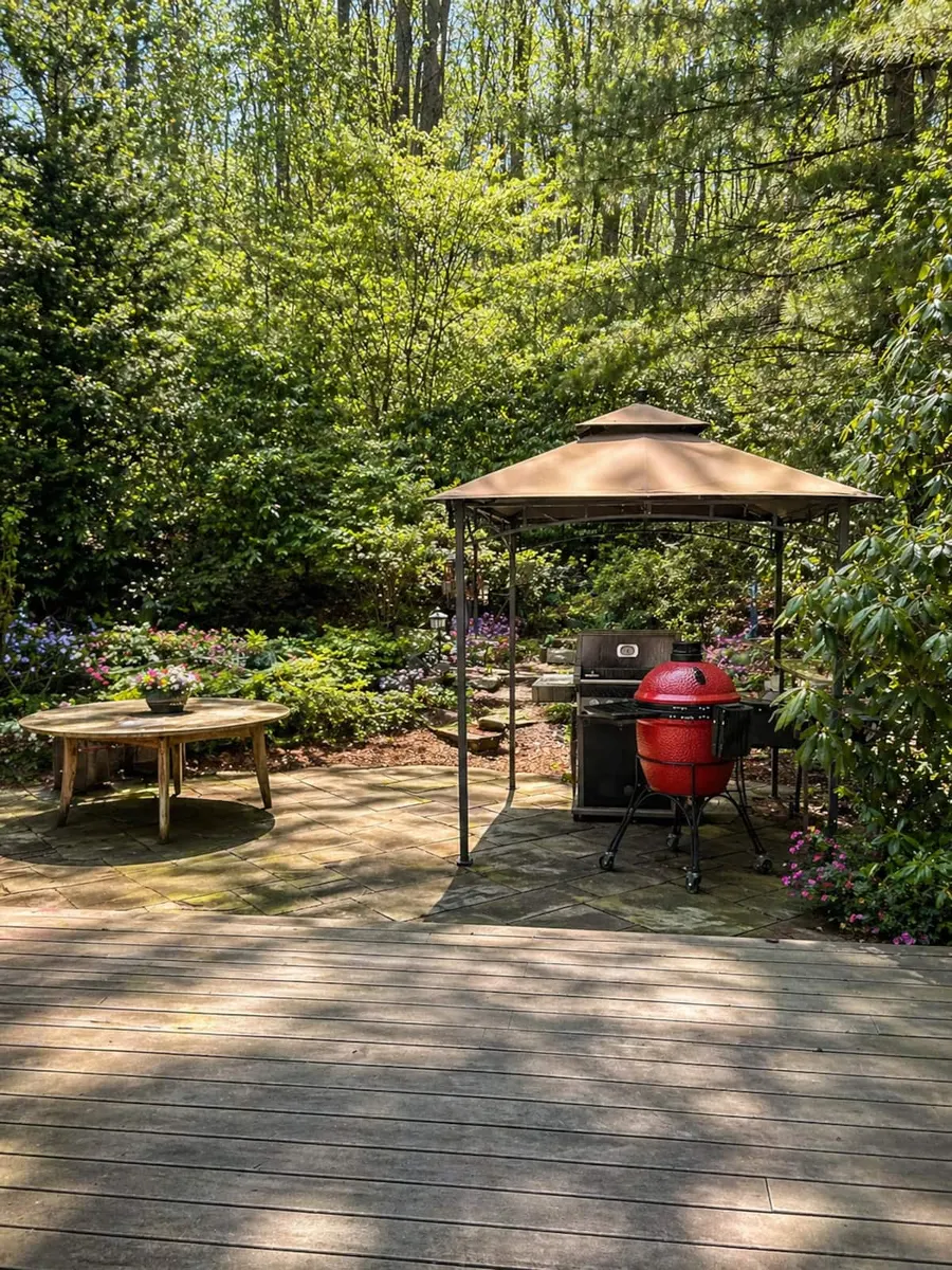 A gazebo on the stone patio among tall trees