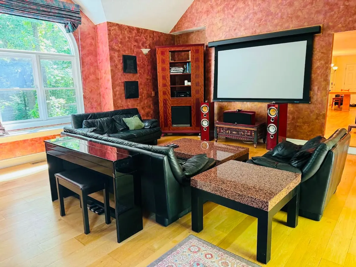 A media room with a large projector screen, leather sofas and warm terracotta walls